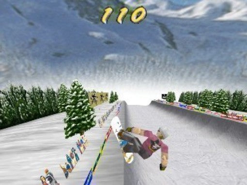 Ein Snowboarder in pinkem Shirt springt in einer Halfpipe, umgeben von verschneiten Bergen und Tannen.