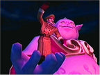 Ein Mann in Uniform mit roter Mütze steht auf der Schulter eines großen, pinkfarbenen lächelnden Monsters.