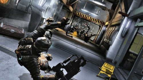 Isaac Clarke zielt mit seiner Waffe auf eine Horde Necromorphs, die durch eine aufgebrochene Tür stürmen.