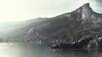 Eine malerische Küstenstadt mit Bergen im Hintergrund ist in Dishonored 2 zu sehen.