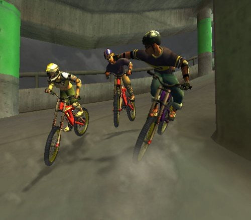 Drei Mountainbiker fahren in einem Tunnel, der von grünen Säulen gestützt wird und Staub aufwirbelt.