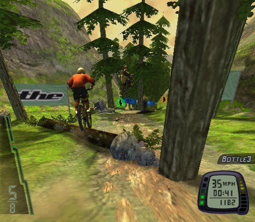 Ein Mountainbiker fährt auf einer Waldstrecke über einen Baumstamm, rechts unten ist ein Tacho zu sehen.