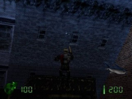 Duke Nukem steht auf einem Dach und blickt zu einem dunklen Gebäude mit Fenstern hinauf, rechts fliegt ein kleiner Hai.