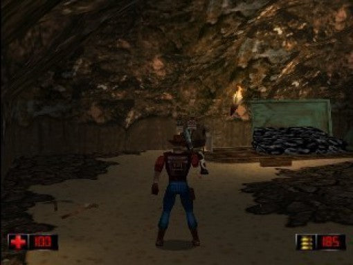 Duke Nukem im Cowboy-Outfit steht in einer Höhle vor einem Gegner und einem Haufen schwarzer Steine.