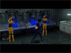 Eine Frau in blauem Anzug steht in einem Raum mit zwei gelb gekleideten Figuren und technischen Geräten.