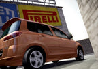 Ein oranger Kombi fährt an einer Mauer vorbei, im Hintergrund ist eine grosse Pirelli-Werbung.