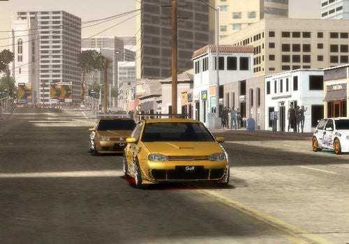 Zwei goldene Volkswagen Golf Sportwagen fahren auf einer breiten Stadtstraße mit hohen Gebäuden im Hintergrund.