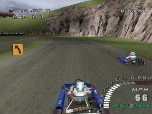 Ein Go-Kart fährt auf einer Rennstrecke entlang einer Felswand, mit einem weiteren Go-Kart im Bild.