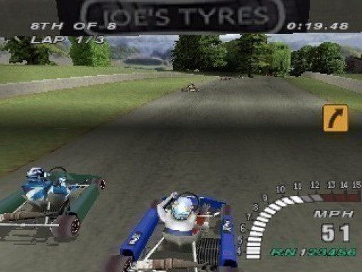 Zwei Go-Karts fahren auf einer Landstraße, umgeben von Bäumen und Hügeln, mit einem Tachometer.