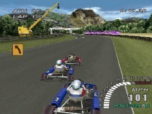 Drei Karts fahren auf einer Rennstrecke mit grünen Hügeln und einem gelben Kran im Hintergrund.
