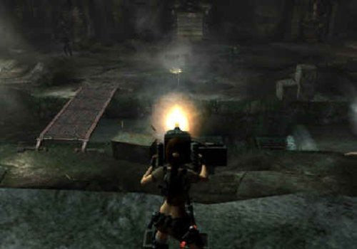 Lara Croft feuert in einem dunklen, unterirdischen Gang mit einer Waffe, deren Mündung hell leuchtet.