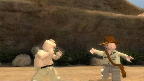Zwei LEGO-Figuren, darunter Indiana Jones, stehen sich in einer felsigen Wüstenlandschaft gegenüber.