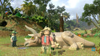 In LEGO Jurassic World steht eine blonde Lego-Figur vor einem Triceratops in einer Dschungellandschaft.