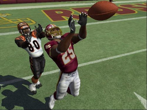 Zwei American-Football-Spieler in roten und orangefarbenen Trikots versuchen, einen Football zu fangen.