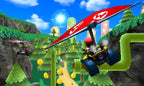 Ein Fahrer mit Gleiter fliegt in Mario Kart 7 für Nintendo 3DS über eine waldige Strecke mit Münzen.