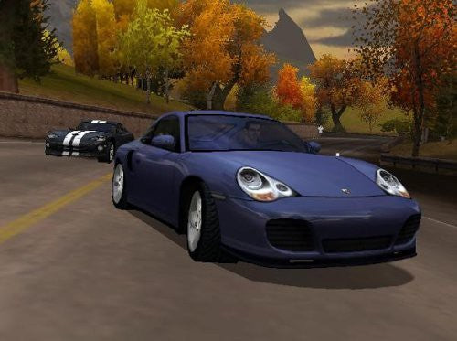 Ein blaues Sportauto fährt auf einer Straße durch eine herbstliche Landschaft.