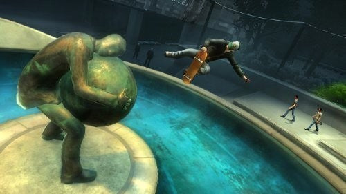 Ein Skater springt über einen Brunnen, neben einer Statue, die eine Kugel trägt.