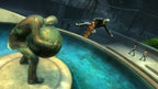 Ein Skater springt über einen Brunnen, neben einer Statue, die eine Kugel trägt.