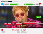 Elton John singt in einem pinken Anzug mit Sonnenbrille am Mikrofon, dazu der Songtext "I'm a rock-et man".