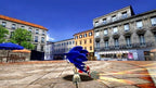 Sonic rennt mit hoher Geschwindigkeit über einen sonnigen Stadtplatz mit Gebäuden und Tischen.