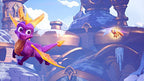 Der lila Drache Spyro fliegt mit einem kleinen, orangen Drachen vor einer verschneiten Burg.