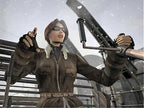 Kate Walker mit Sonnenbrille und brauner Jacke sitzt im Cockpit eines Flugzeugs und bedient die Steuerung.