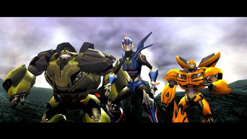 Drei Autobots, darunter Bulkhead, Arcee und Bumblebee, stehen zusammen vor einem bewölkten Himmel.